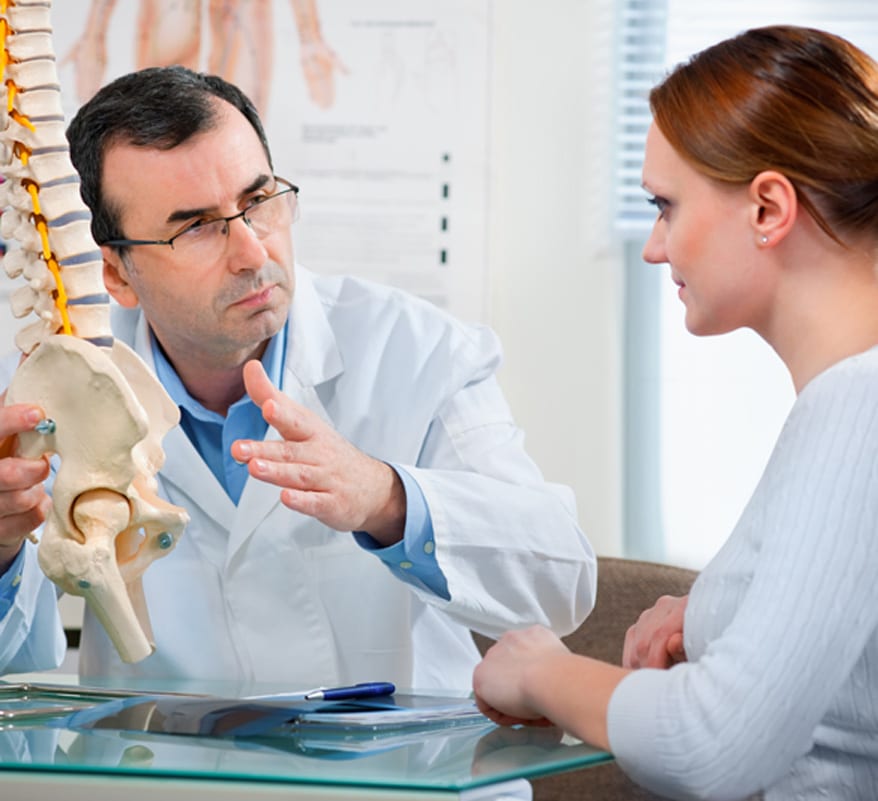 Male-physician-explaining-the-spine-to-female-patient