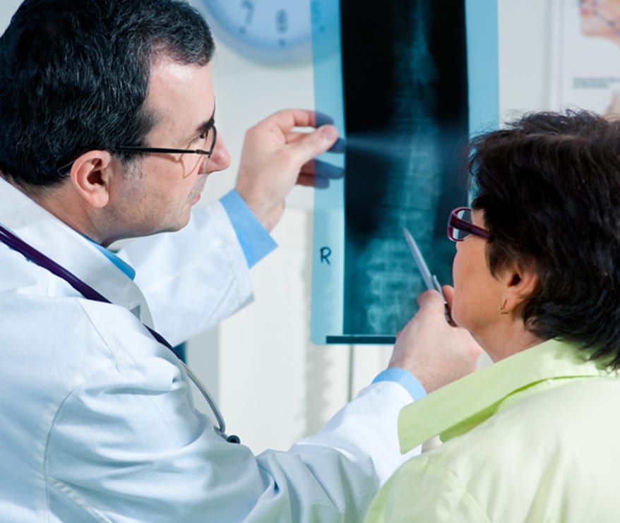 Male-physician-holding-up-x-ray-of-female-patient’s-spine