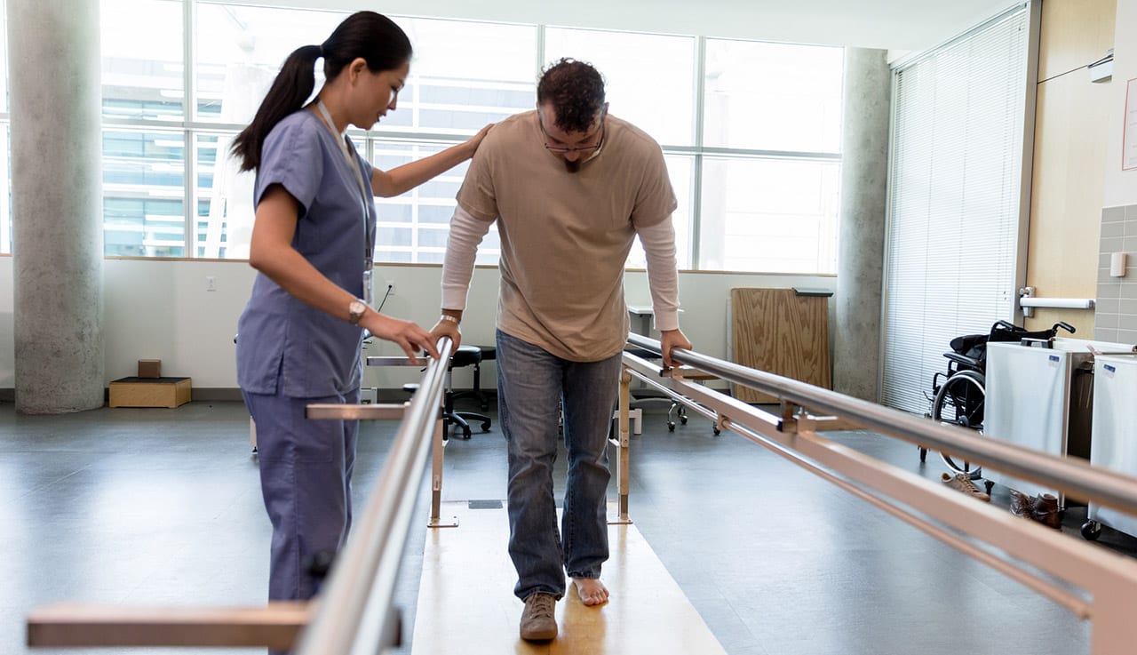 Physical-therapist-helping-a-patient-walk-after-knee-replacement-surgery
