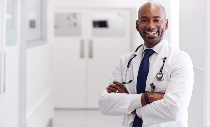 Orthopedic-spine-specialist-wearing-a-white-lab-coat-and-smiling,-with-his-hands-folded