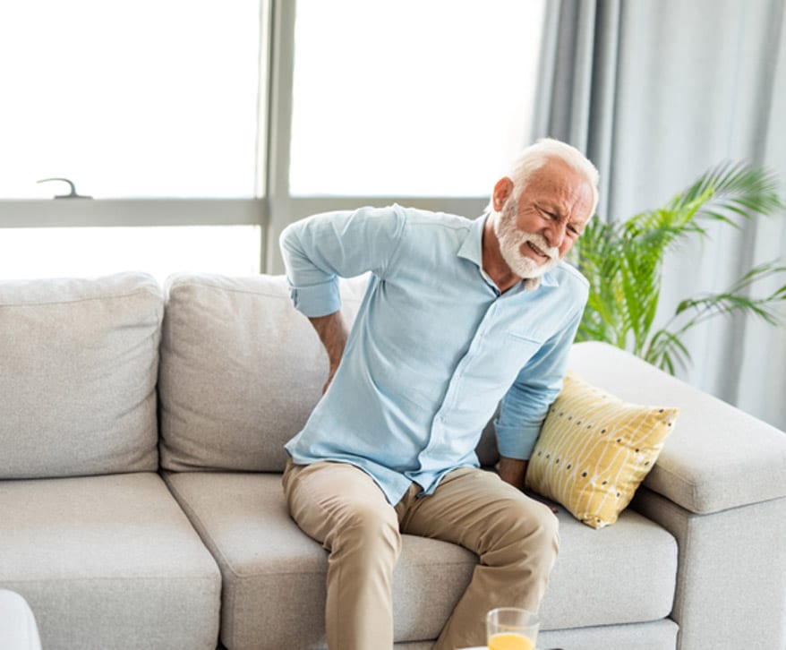 Senior-male-sitting-on-couch-and-experiencing-lower-back-pain